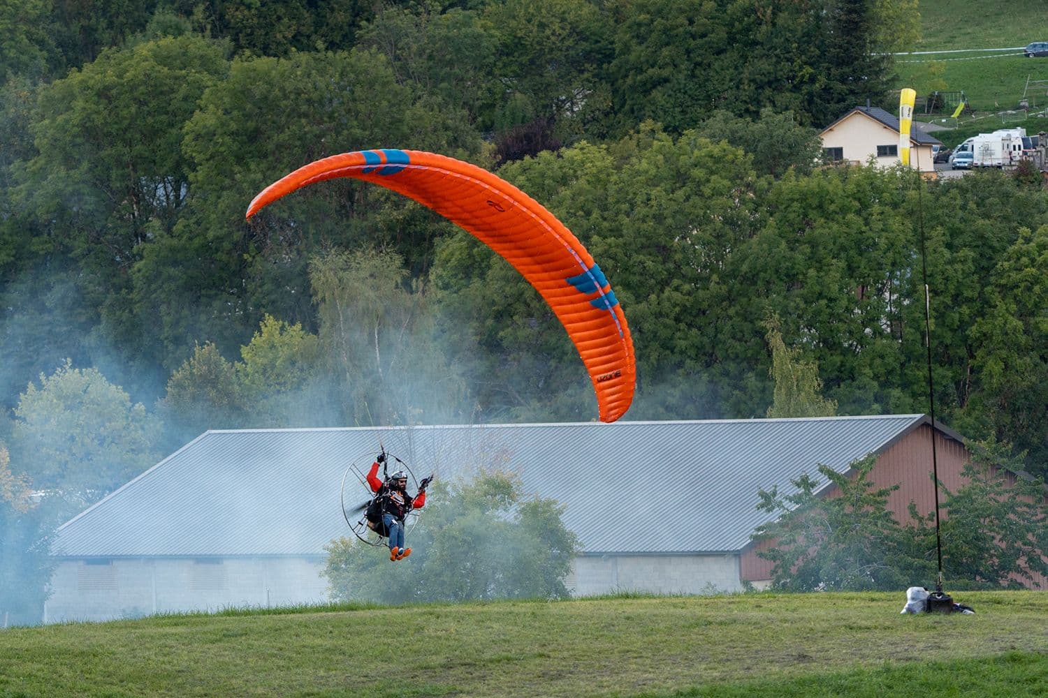Pilot kiting a paramotor wing in a misty field
