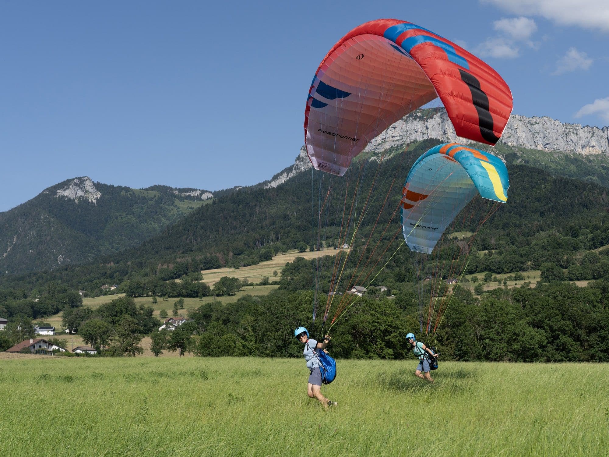 Pilots kiting paramotor wings in a grassy field