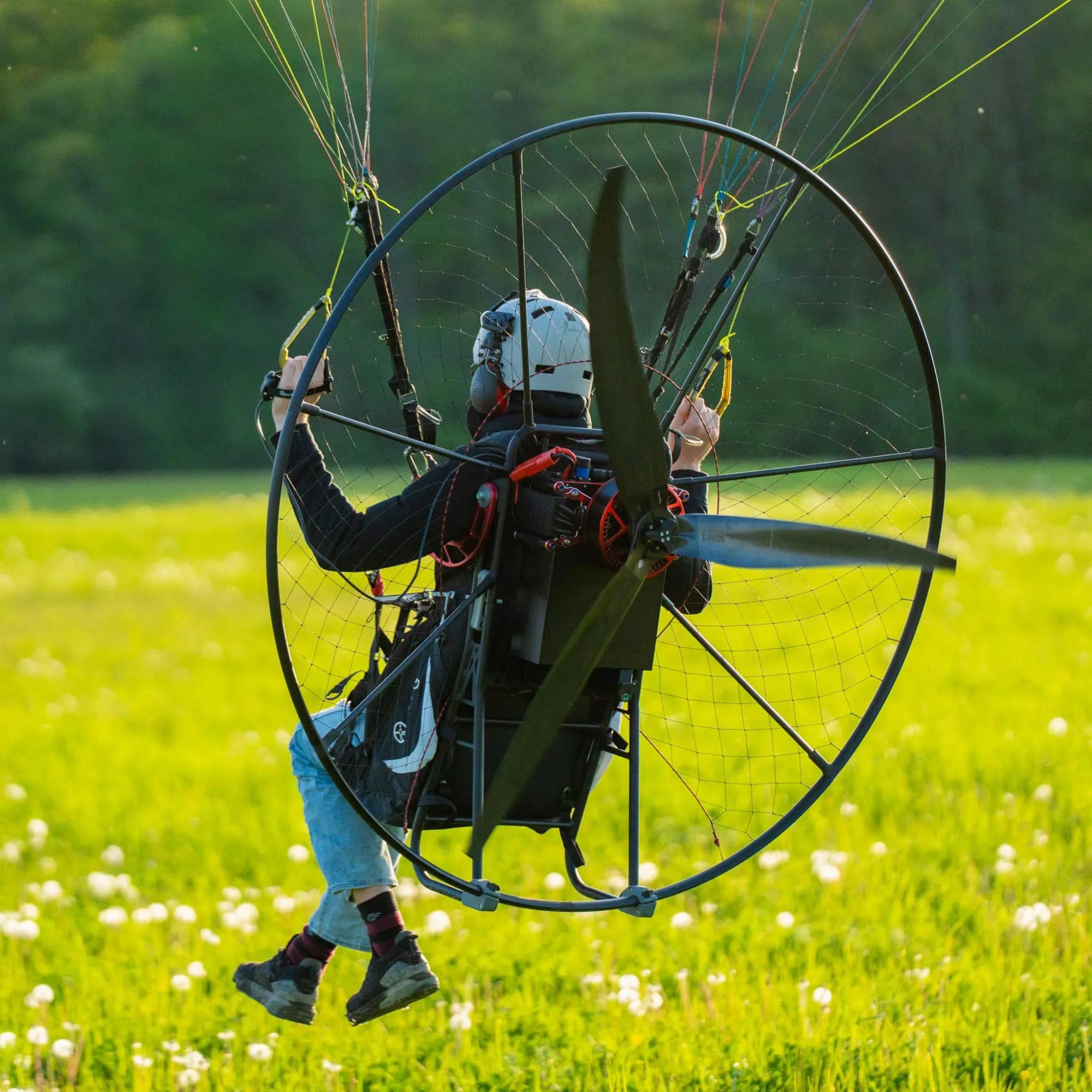 Paramotor pilot silhouetted against a golden sunset
